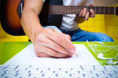 asian professional composer hands writing songs on white paper with acoustic guitar & computer clipart
