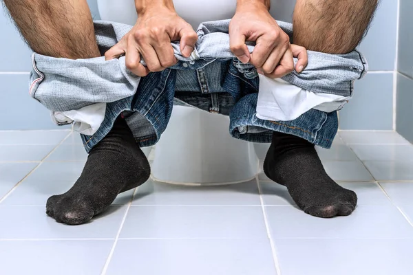 Man sitting on toilet, diarrhea Stock Photo