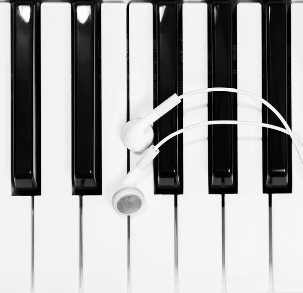 Earphones on piano keys, black and white — Stock Photo, Image