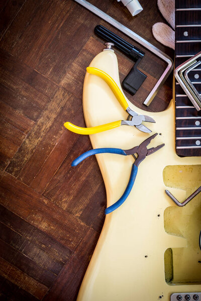 yellow electric guitar on wood in repair & luthier workshop, fixing & musical instrument repairing concept