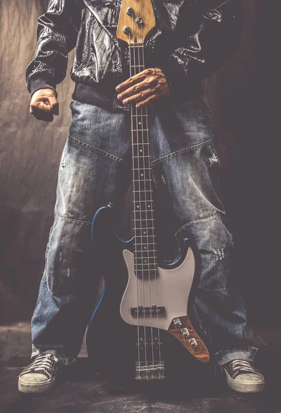 Mannelijke zanger in leren jasje, spijkerbroek houden van elektrische basgitaar — Stockfoto