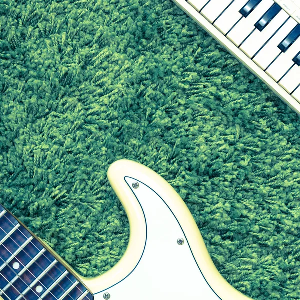 Deel van de elektrische gitaar en muziek keyboard op groen — Stockfoto