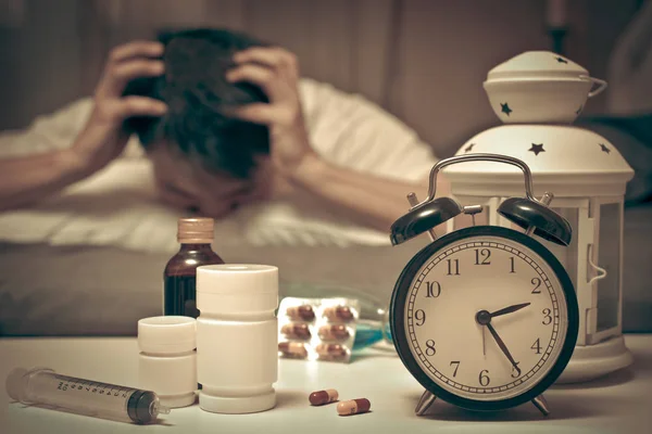 Homme asiatique au lit avec des comprimés et des médicaments souffrant d'insomnie, gueule de bois, maux de tête la nuit — Photo