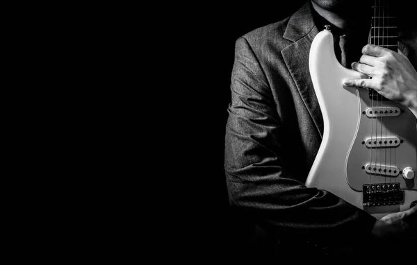 Musicista maschile in abito grigio con chitarra elettrica su sfondo scuro — Foto Stock