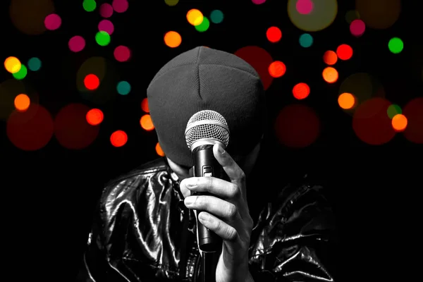 Férfi ázsiai énekes pózol a dinamikus mikrofon bokeh színes háttérrel — Stock Fotó