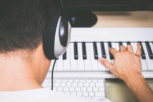 Rückansicht eines asiatischen männlichen professionellen Komponisten, der Songs mit Studio-Keyboard und Computer komponiert. Konzept der Musikproduktionstechnologie — Stockfoto