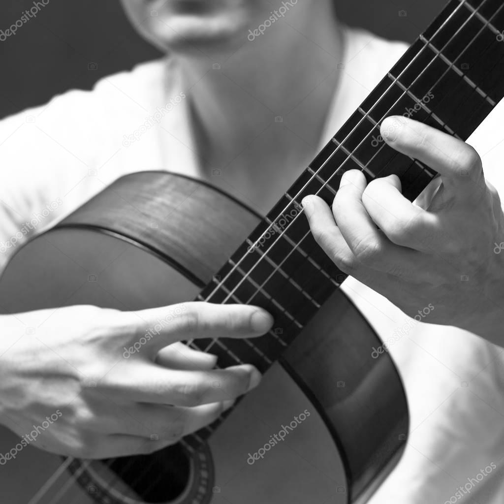 male musician playing classical, acoustic guitar