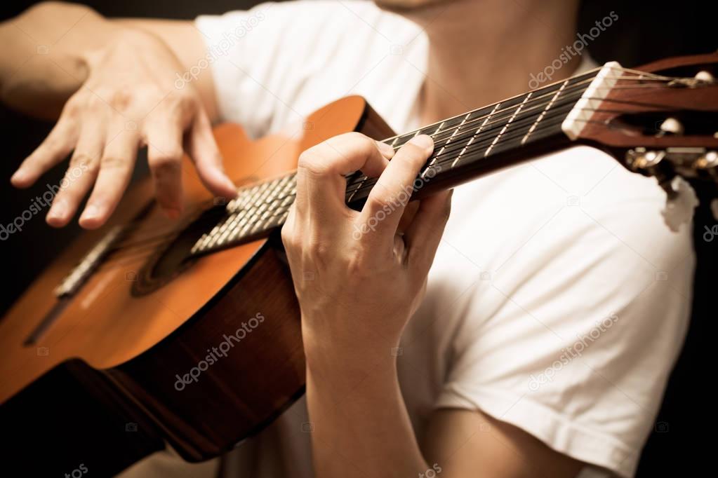 asian musician hands playing acoustic guitar