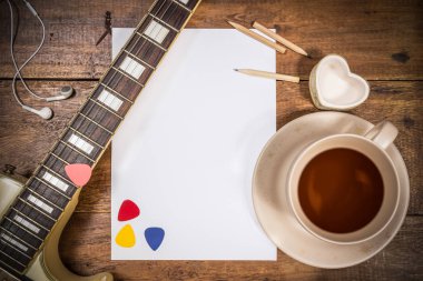 elektro gitar, boş beyaz kağıt ve bir fincan çay ahşap tablo