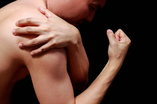Asiatique homme montrant son muscle dans la douleur, isolé sur noir — Photo