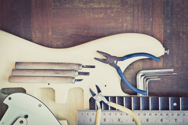 yellow electric guitar on wood in repair & luthier workshop, fixing & musical instrument repairing concept