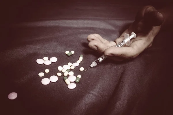 Überdosis asiatischer Drogenabhängiger auf dem Bett, Betäubungsspritze in der Hand — Stockfoto