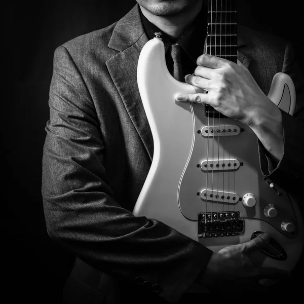 Musicista maschile in abito grigio con chitarra elettrica su sfondo scuro — Foto Stock