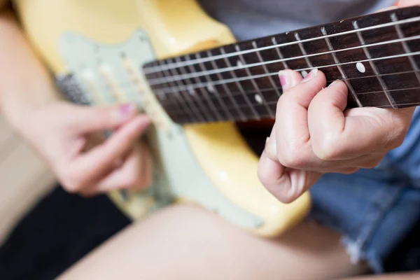 female teen musician playing electric guitar
