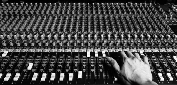 right hand of sound engineer working on recording studio mixer