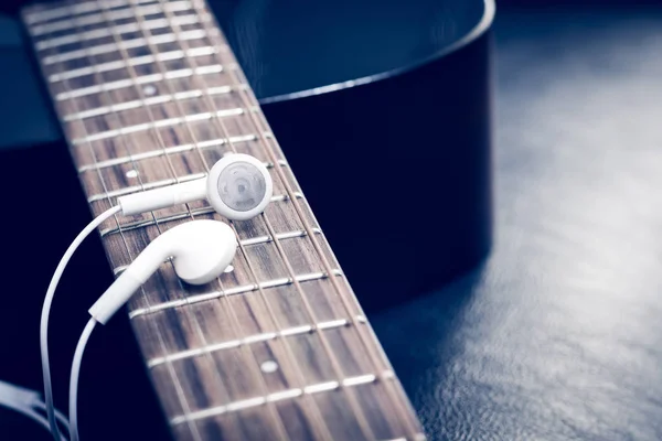 Fones de ouvido brancos na guitarra acústica fingerboard para fundo de música — Fotografia de Stock