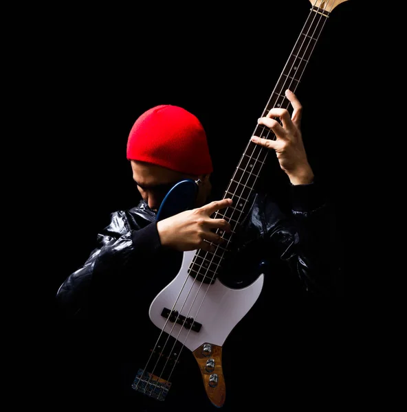 asian professional musician in leather jacket, red hat playing electric bass guitar