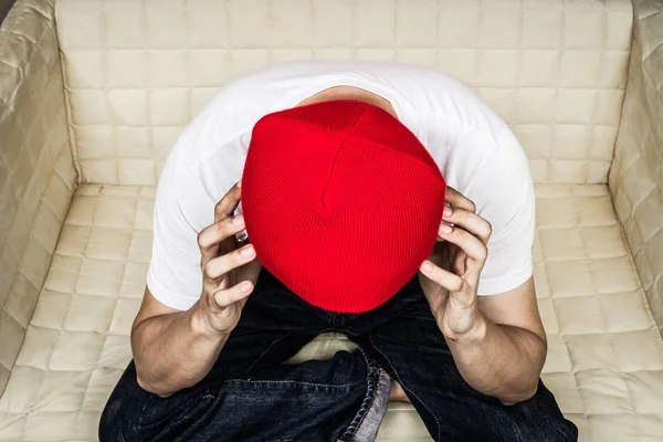 Dolor de cabeza, infeliz asiático adolescente en sombrero rojo, camiseta blanca y pantalones vaqueros azules en asiento amarillo para el fondo de salud — Foto de Stock
