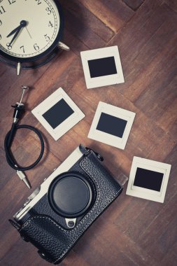 Klasik rangefinder fotoğraf makinesi ile vintage slayt film ve ahşap zemin üzerinde eski saat