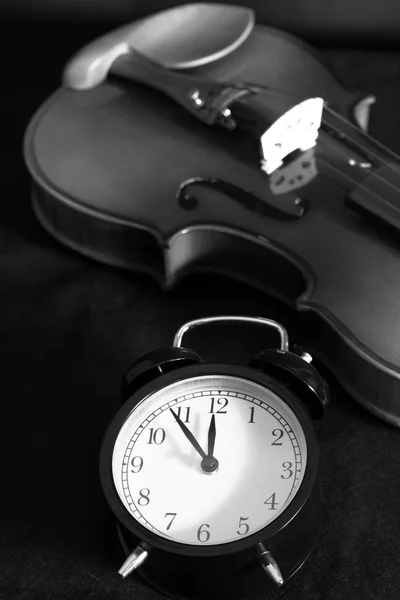 Väckarklocka & gammal klassisk fiol på svart tyg — Stockfoto