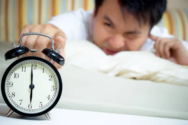 Dormir asiatique jeune mâle perturbé par réveil tôt le matin sur lit — Photo