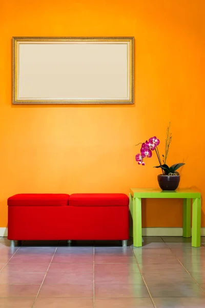 Chaise tabouret rouge, fleurs sur table verte, et cadre photo sur mur orange — Photo