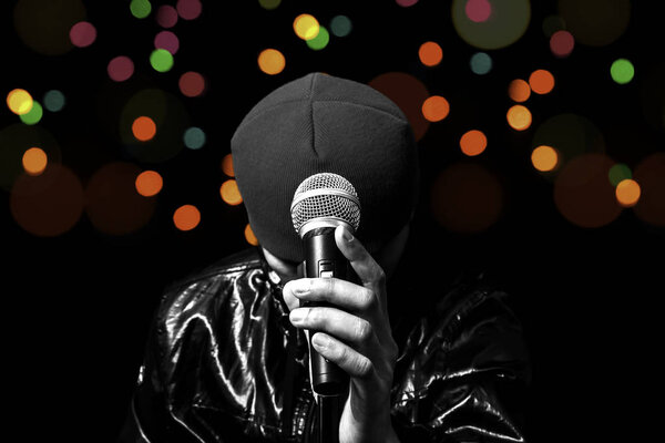 asian vocalist holding dynamic microphone with colourful bokeh in concert