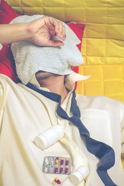 Asiatique ivrogne homme d'affaires couché sur un fauteuil jaune avec des comprimés et des médicaments souffrant d'insomnie, gueule de bois et maux de tête la nuit — Photo