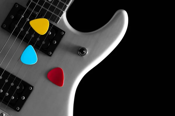 Colourful picks on black and white electric guitar — Stock Photo, Image