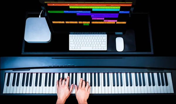 Технология производства музыки, руки композитора, работающего над клавишами фортепиано с компьютером на столе — стоковое фото