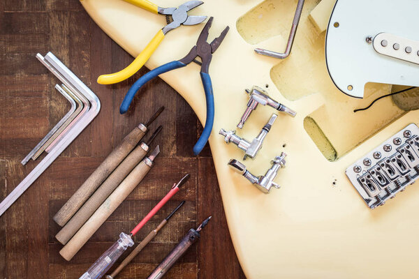 yellow electric guitar on wood in repair & luthier workshop, fixing & musical instrument repairing concept