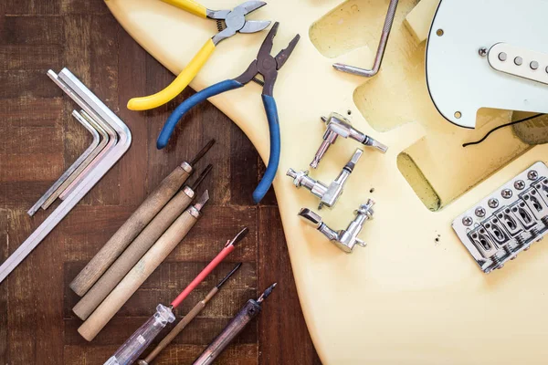 Yellow electric guitar on wood in repair & luthier workshop, fixing & musical instrument repairing concept Stock Photo