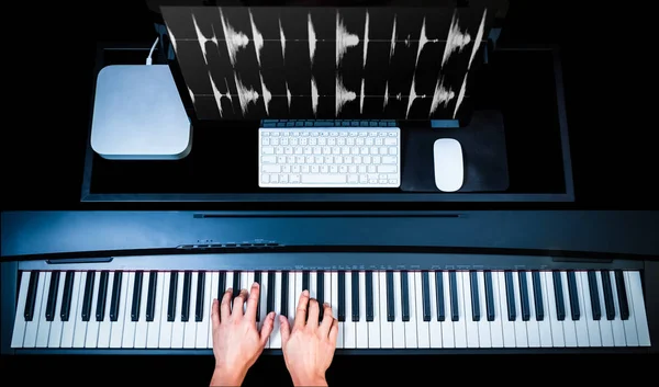 music production technology, male composer hands working on piano keys with computer on desk