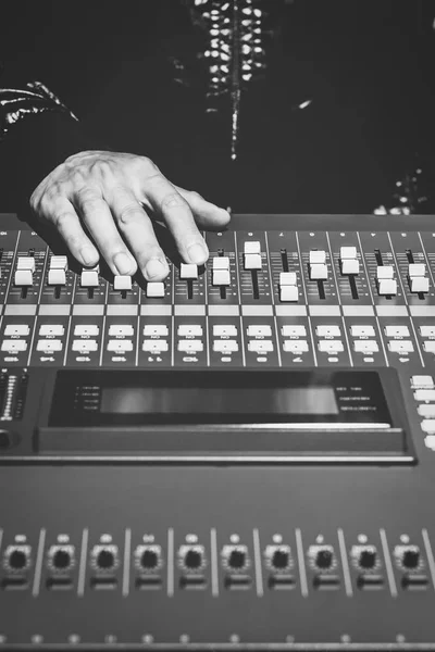 sound engineer hands working on sound mixer in digital music editing studio or live concert, black and white