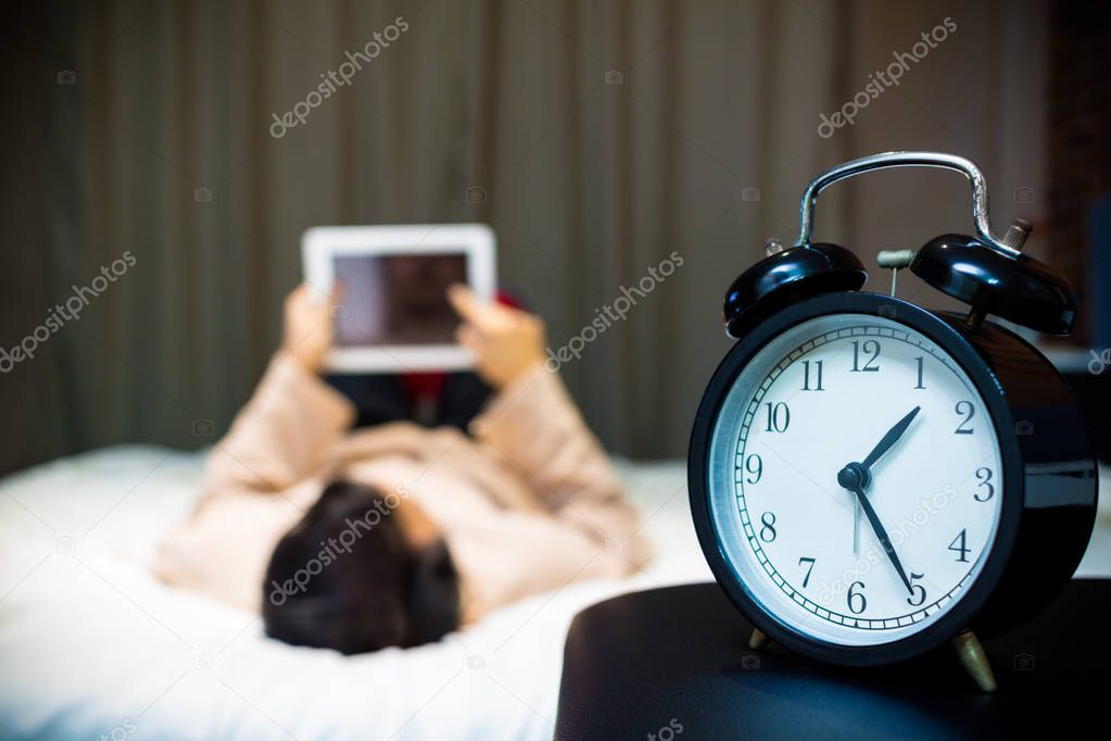 asian man playing tablet pc in bed suffering insomnia and sleep disorder at night