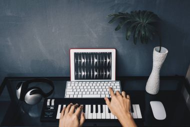 küçük bir yer ev stüdyosu kavramı içinde müzik yapım. tablet bilgisayar ve MIDI klavye üzerinde şarkı ile masa üzerinde kulaklık ev stüdyosunda kayıt adam eller