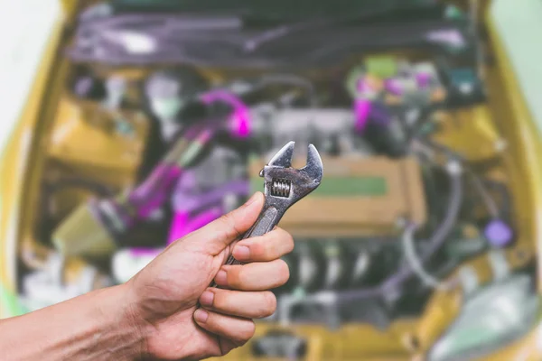 Hand with wrench on modified car engine background — Stock Photo, Image