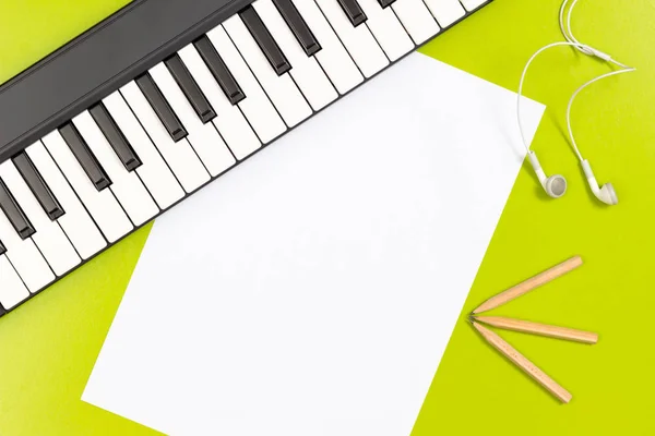 バック グラウンド ミュージック。空白のホワイト ペーパー、鉛筆、イヤホン ・緑の机の上のピアノ — ストック写真