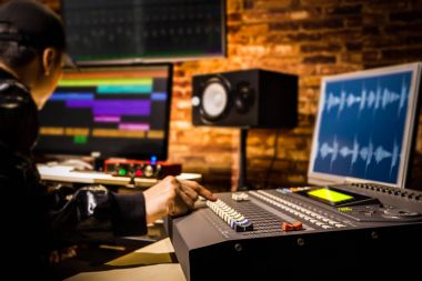 Yayın, studio düzenleme dijital kayıt çalışan Asyalı erkek profesyonel ses mühendisi. Mixer fader üzerinde odaklanmak