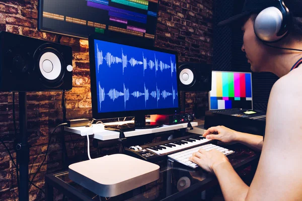 Aziatische mannelijke hipster geluidstechnicus, werken op computer in digitale audio & video post productie montagestudio — Stockfoto