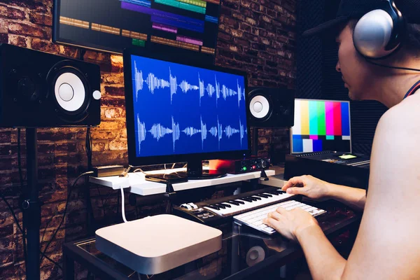 Asian male hipster sound engineer working on computer in digital audio & video editing post production studio Stock Photo