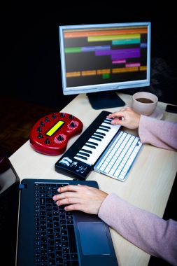 male composer hands using computer, midi keyboard & studio equipment making songs and sound design on desk for post production or music score on film clipart