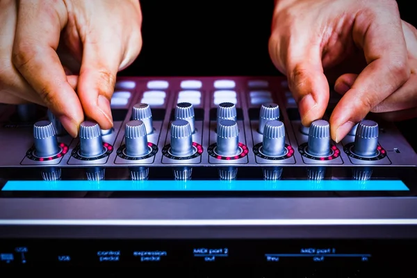 male sound engineer hands tuning knobs of studio gears, digital sound mixer, pre-amp, audio interface, effect signal processor for TV radio broadcasting, post production or music background