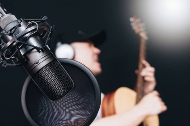 Asyalı erkek müzisyen kayıt stüdyosu, odak mikrofon akustik gitar çalmak
