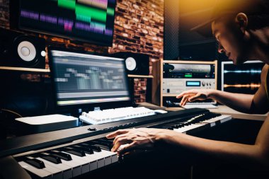 Asyalı erkek müzik aranjör eller MIDI piyano ve profesyonel olarak şarkı beste dijital kayıt Studio ses ekipmanları