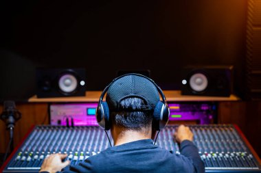 Asyalı profesyonel müzik yapımcısı, ses mühendisi kayıt stüdyosunda ses karıştırma konsolunda şarkı yapıyor. müzik üretimi, post prodüksiyon konsepti