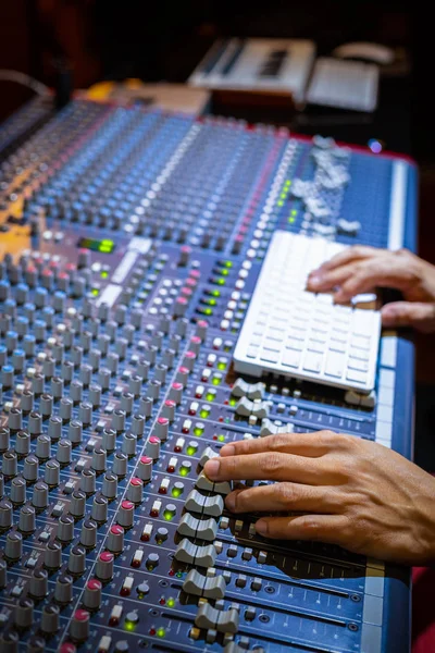 male producer, sound engineer hands working on audio mixing console in broadcasting, recording studio