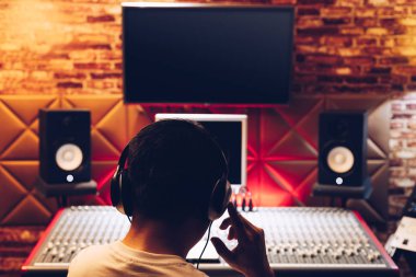 Kayıt stüdyosunda ses karıştırma konsolu üzerinde çalışan Asyalı erkek müzik yapımcısının arkası. müzik üretimi, yayıncılık, post prodüksiyon konsepti
