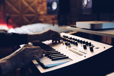 Kayıt stüdyosunda klavye sentezleyicisi çalan erkek müzisyen elleri