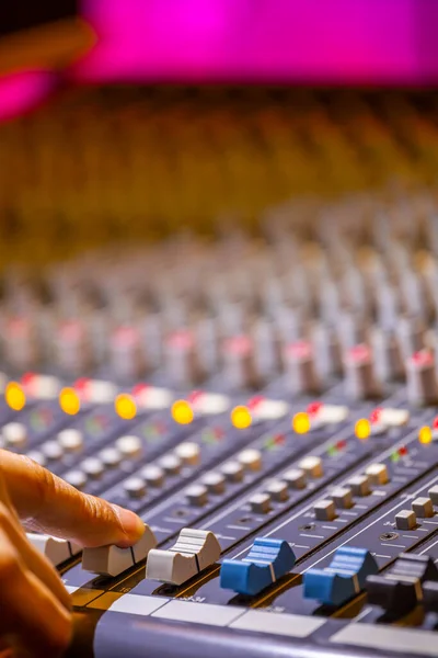 sound engineer fingers adjusting on audio mixing console fader. recording, broadcasting concept